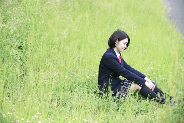 草むらに座る女子学生