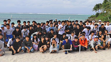 沖縄の海辺で集合写真を撮影する生徒たち